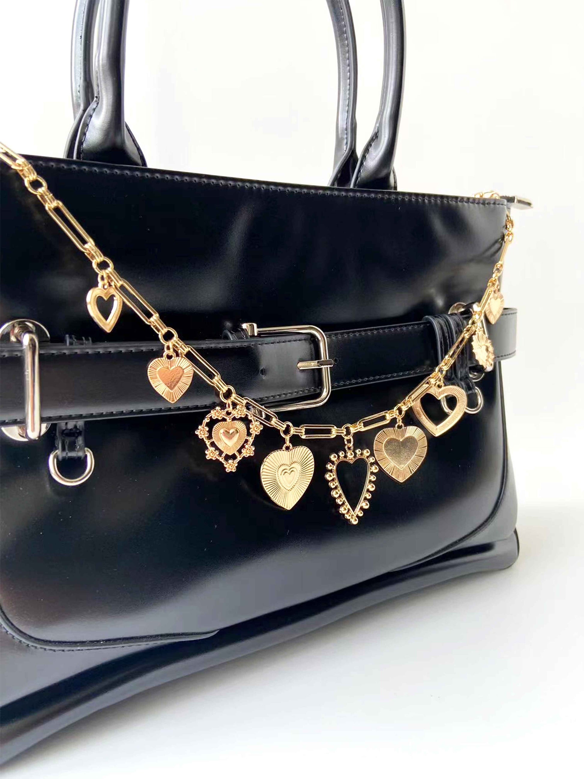 Golden heart pendant chain adorns black bag, eye - catching and stylish.