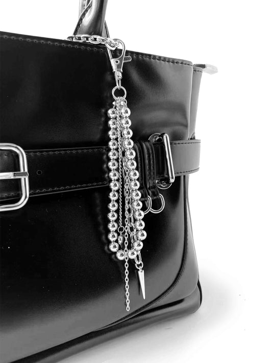 Close-up of black handbag side, showing bead chain and spike pendant details, premium texture.