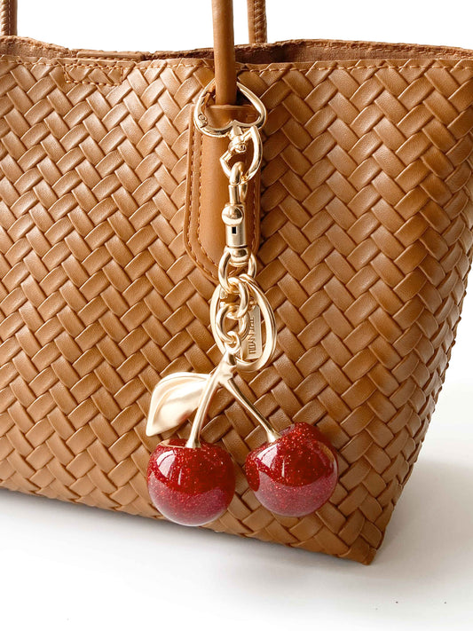 Brown woven handbag with cherry metal keychain, stylish and versatile