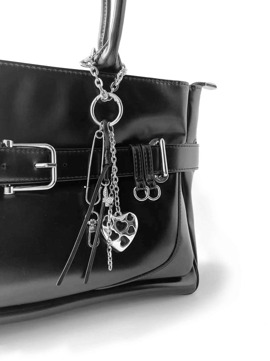 Black glossy leather handbag with heart and pin metal charms, simple and stylish.