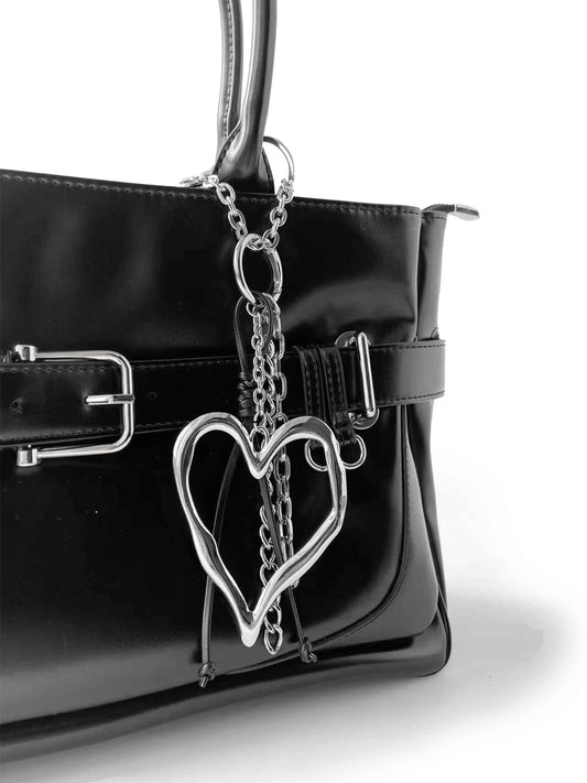Smooth black leather handbag with hollow heart-shaped metal pendant, simple and stylish.