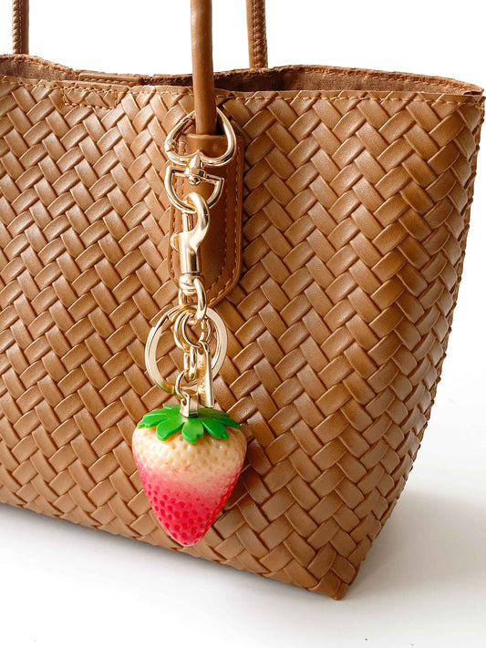 Strawberry - shaped bag charm adds a cute touch to the brown woven bag.