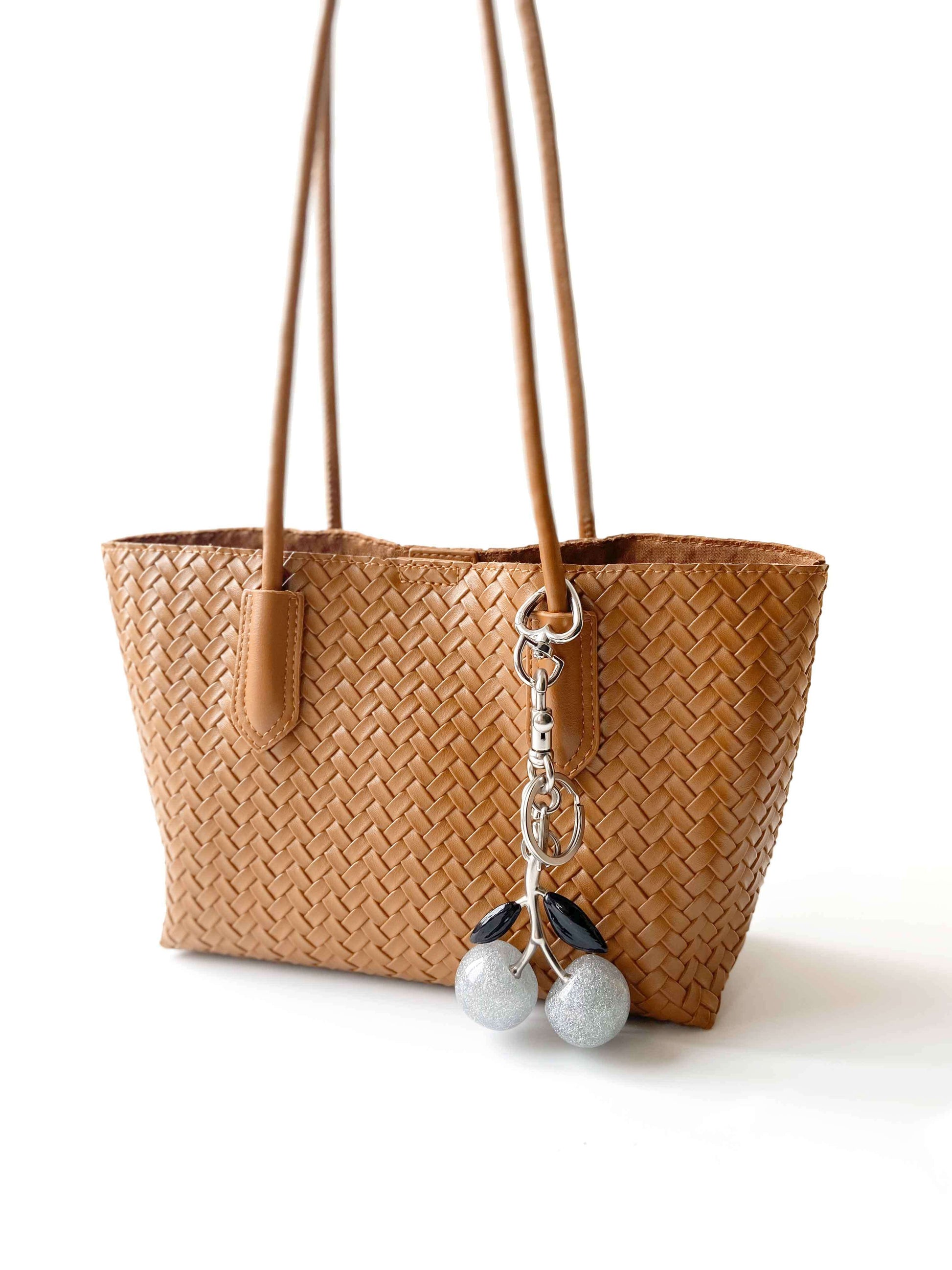 Brown woven handbag with silver cherry charm, combining fashion and function