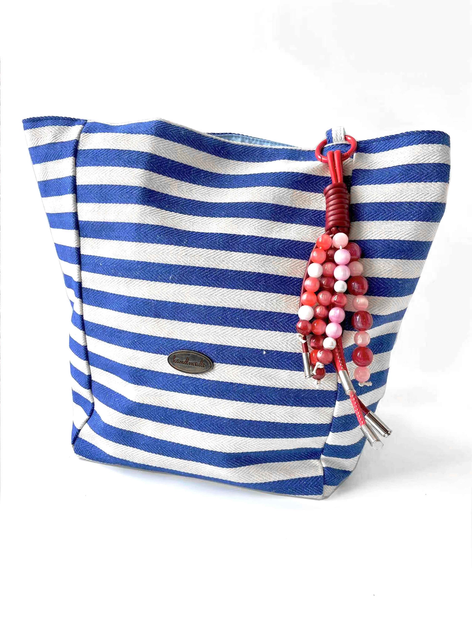 Pink - red beaded leather tassel charm adds color to the blue - white striped bag.